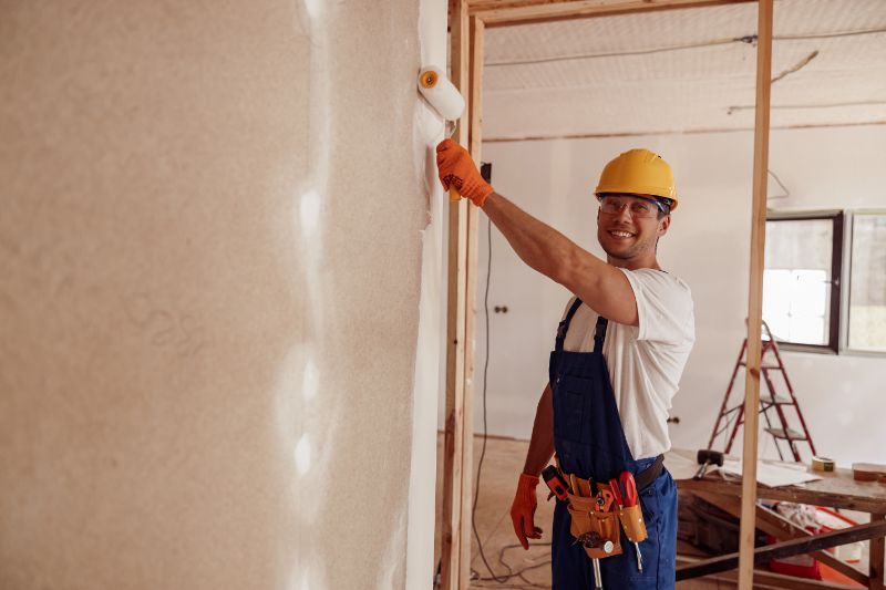 A painter in safety helmet and smiling while painting the wall